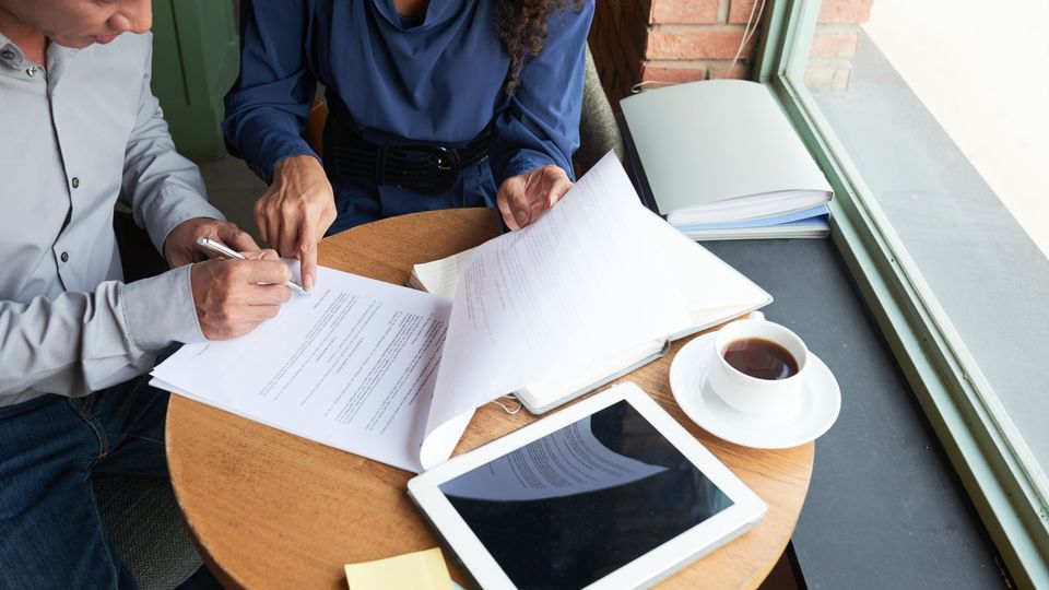 Duas pessoas assinando um contrato sobre a mesa